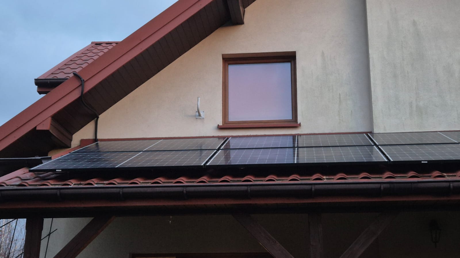Panele fotowoltaiczne na dachu skośnym z czerwoną dachówką