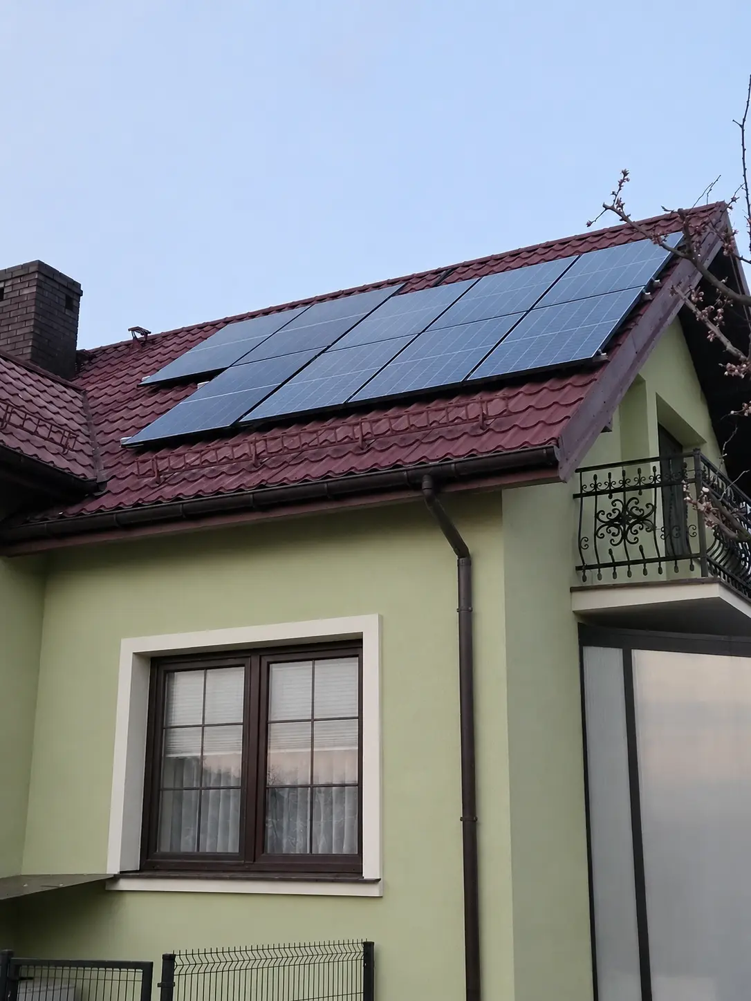Panele fotowoltaiczne na dachu z czerwoną dachówką